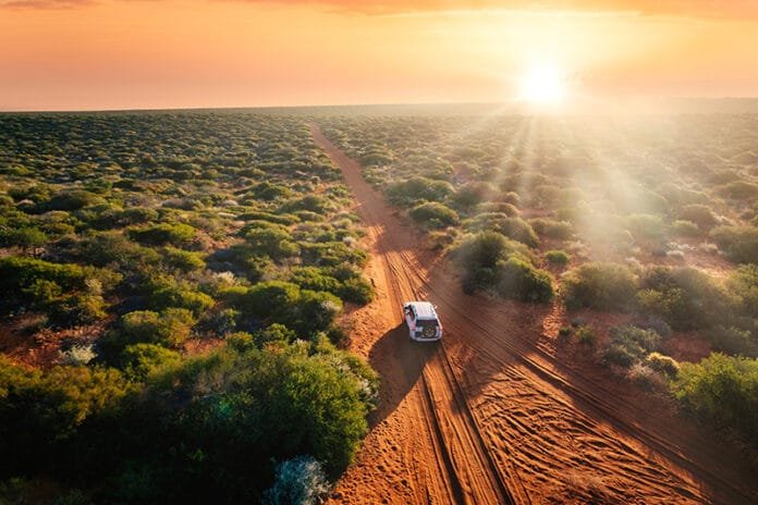 Australia, red sand unpaved road and 4x4 at sunset, freedom outback Australia Getaway